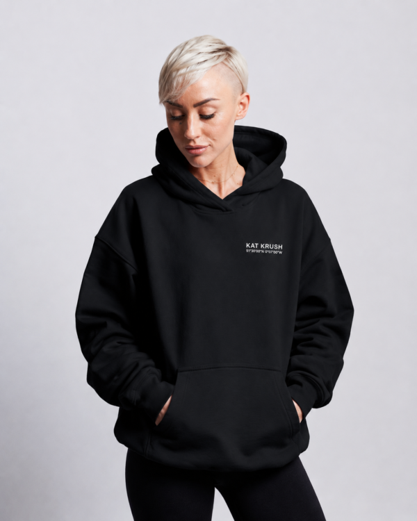 Waist-up portrait of oversized Kat Krush hoodie showing relaxed drape, dropped shoulders and structured heavyweight silhouette with hands in pockets.