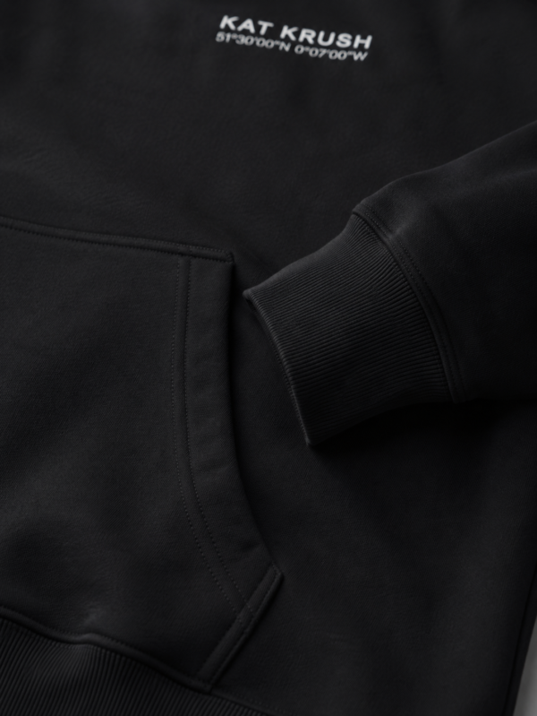 Macro close-up of heavyweight hoodie pocket, ribbed cuff and premium stitching details highlighting structured cotton construction and quality finish.