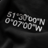 Close-up macro shot of a black heavyweight hoodie featuring white London coordinates print. Detailed fabric texture, visible knit structure, and soft folds highlight the premium material quality and clean high-contrast print finish.