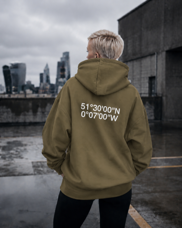 kk-hoodie-london-khaki-concrete Khaki oversized London coordinates hoodie styled on rooftop overlooking London skyline. Minimal streetwear aesthetic with cinematic concrete setting and relaxed oversized fit.