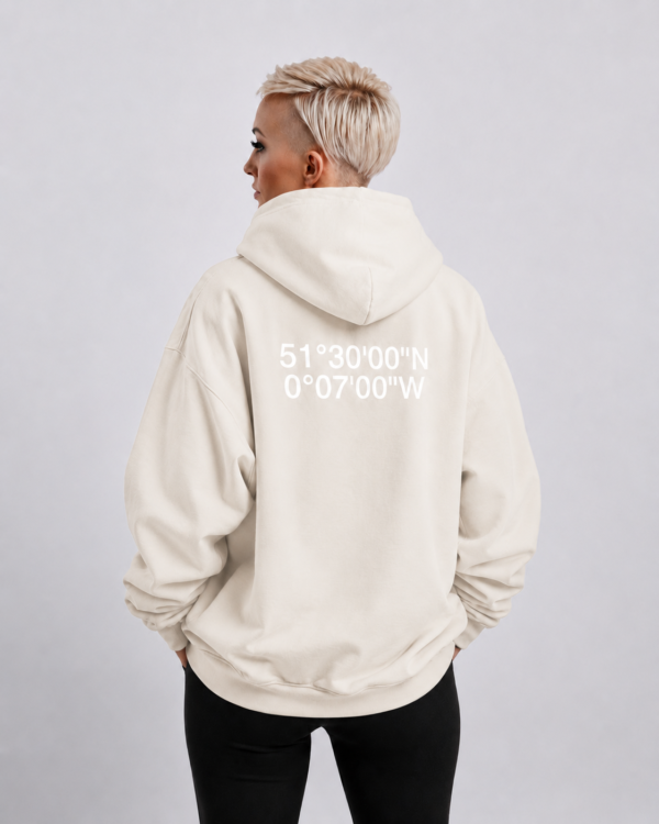 Waist-up fit shot of Natural Raw oversized hoodie with London coordinates back print. Clean oversized silhouette with dropped shoulders and minimal streetwear styling.