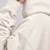Detailed fabric close-up of Natural Raw oversized hoodie showing heavyweight organic cotton texture, shoulder seam detail, ribbed cuff, and premium construction