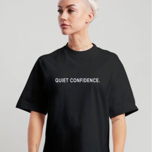 Woman wearing black oversized Quiet Confidence T-Shirt by Kat Krush against a light grey background