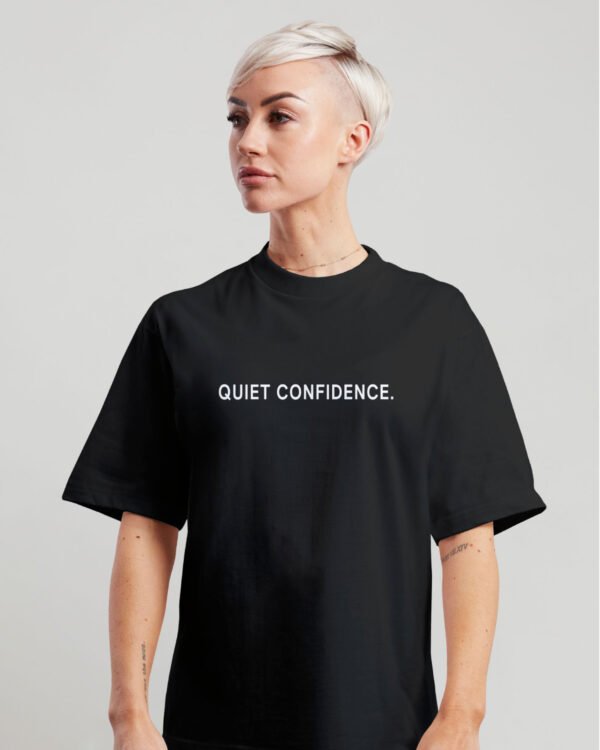 kk-tee-Quiet-Confidence-black-g-kk Woman wearing black oversized Quiet Confidence T-Shirt by Kat Krush against a light grey background