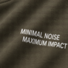 Close-up fabric detail of khaki heavyweight oversized t-shirt with “MINIMAL NOISE MAXIMUM IMPACT” typography print and visible cotton texture folds