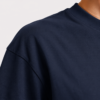Close-up of the shoulder and neckline of a French navy oversized t-shirt showing heavyweight cotton texture, dropped shoulder construction, and premium ribbed collar detail.