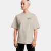 Front-facing studio image of a stone oversized Kat Krush T-shirt featuring a minimalist “Not Loud Just Powerful” chest print and relaxed oversized silhouette.