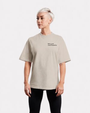 Front-facing studio image of a stone oversized Kat Krush T-shirt featuring a minimalist “Not Loud Just Powerful” chest print and relaxed oversized silhouette.