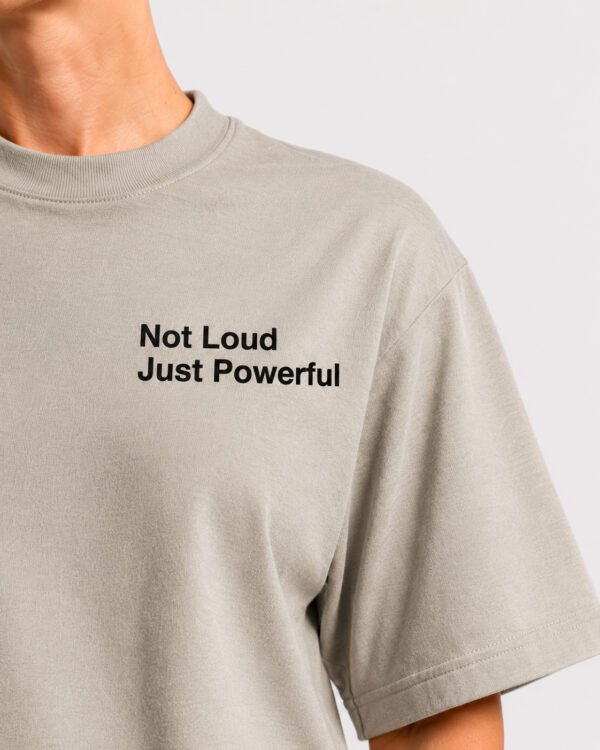 Close-up detail of the “Not Loud Just Powerful” chest print on a stone Kat Krush oversized T-shirt, showcasing the clean typography and premium cotton fabric.