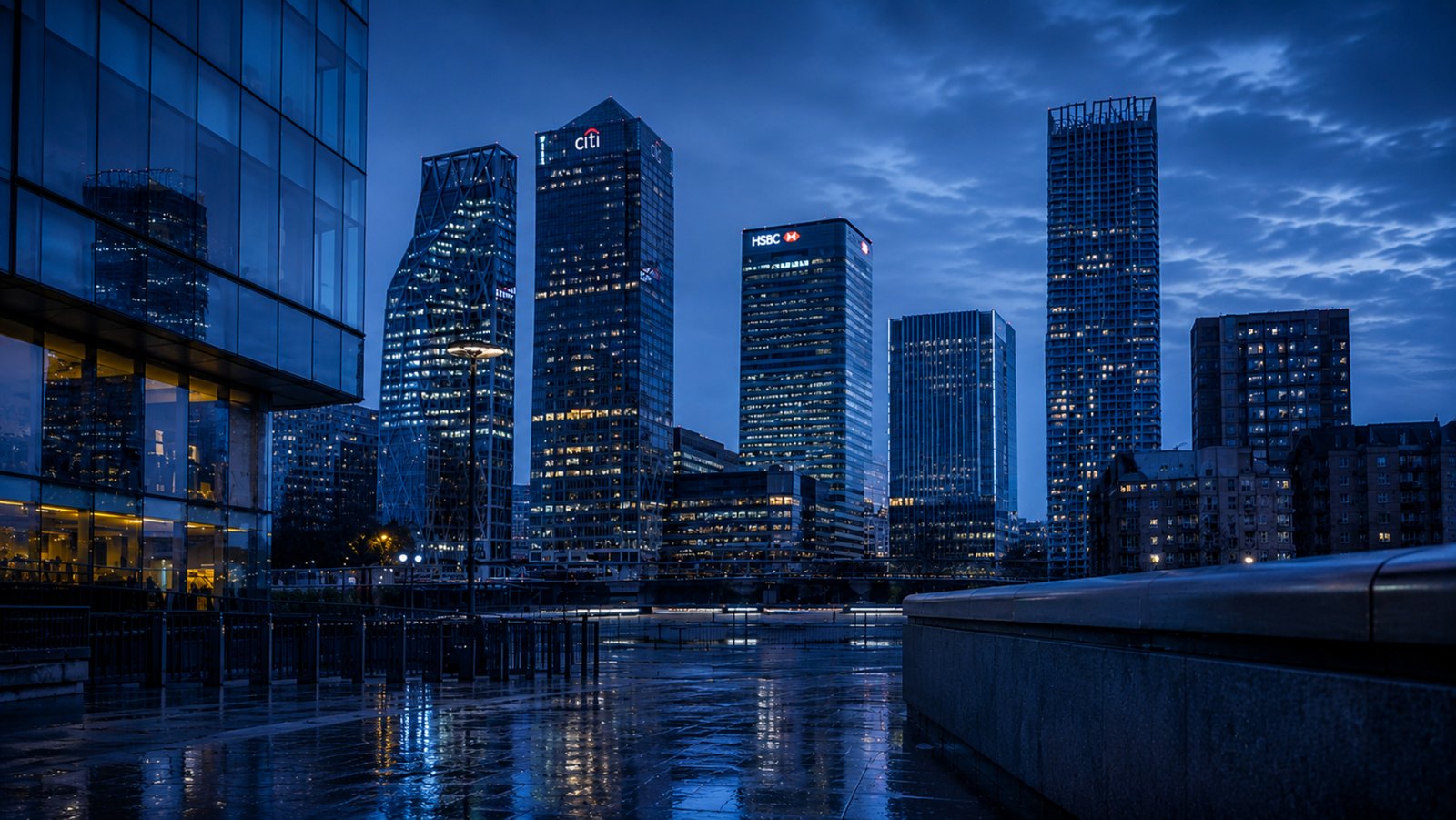 Modern London financial district at blue hour featuring the glass towers of Canary Wharf reflected across rain-soaked paving. Cool silver-blue twilight, dramatic cloud formations and illuminated skyscrapers create a calm, minimalist architectural scene with clean lines, reflective surfaces and a premium editorial streetwear aesthetic, capturing the Quiet Confidence mood without people.