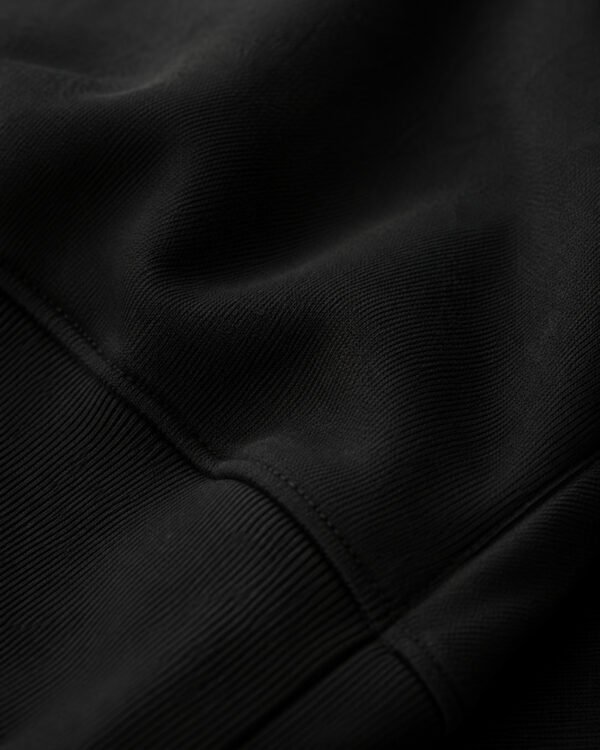 Close-up of black heavyweight hoodie fabric showing detailed knit texture, stitching, and premium construction for everyday streetwear comfort.