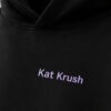 Close-up of black oversized hoodie featuring subtle lilac Kat Krush chest logo. Heavyweight cotton fabric with premium minimal streetwear styling.