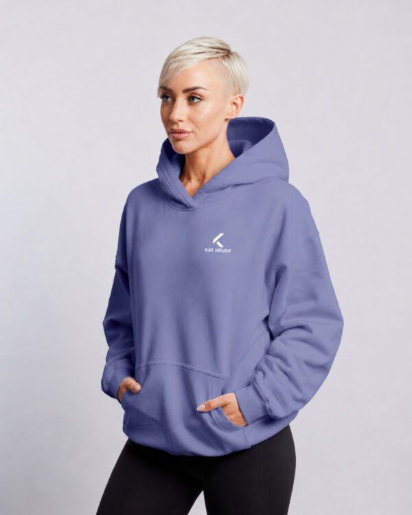 Female model in a violet oversized Kat Krush hoodie, shown from a relaxed side angle with hands in pockets.