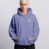 Female model wearing a violet oversized Kat Krush hoodie with hands in pockets in a clean front-facing studio shot.