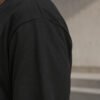 kk-tee-bristol-black-back-fabric Close-up fabric detail of a black oversized Bristol T-shirt showing heavyweight cotton texture, shoulder seam construction and premium finish.