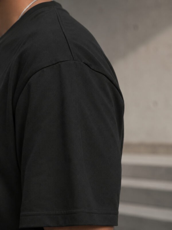 kk-tee-bristol-black-back-fabric Close-up fabric detail of a black oversized Bristol T-shirt showing heavyweight cotton texture, shoulder seam construction and premium finish.
