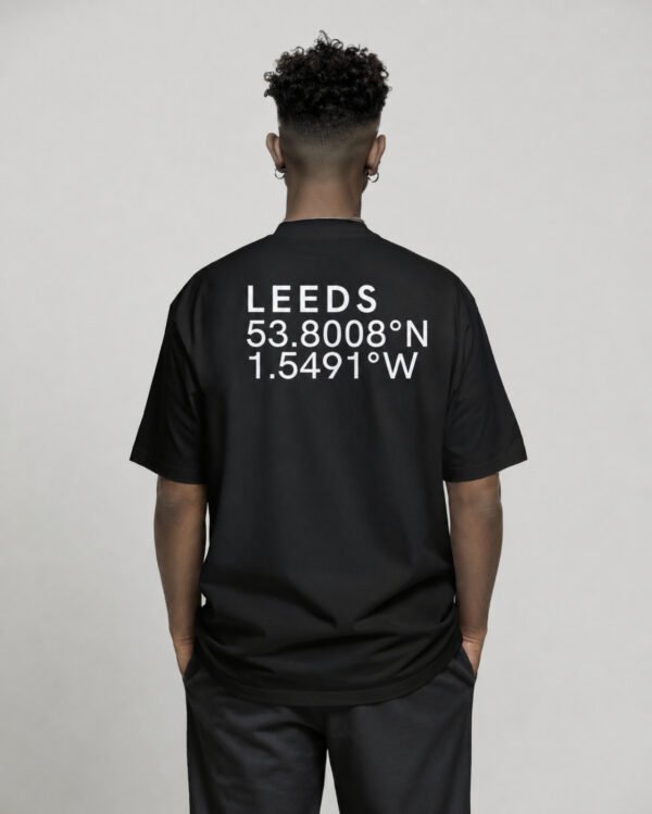 Black oversized Leeds coordinates T-shirt featuring Leeds city coordinates printed on the back, worn by a model in a relaxed studio setting.