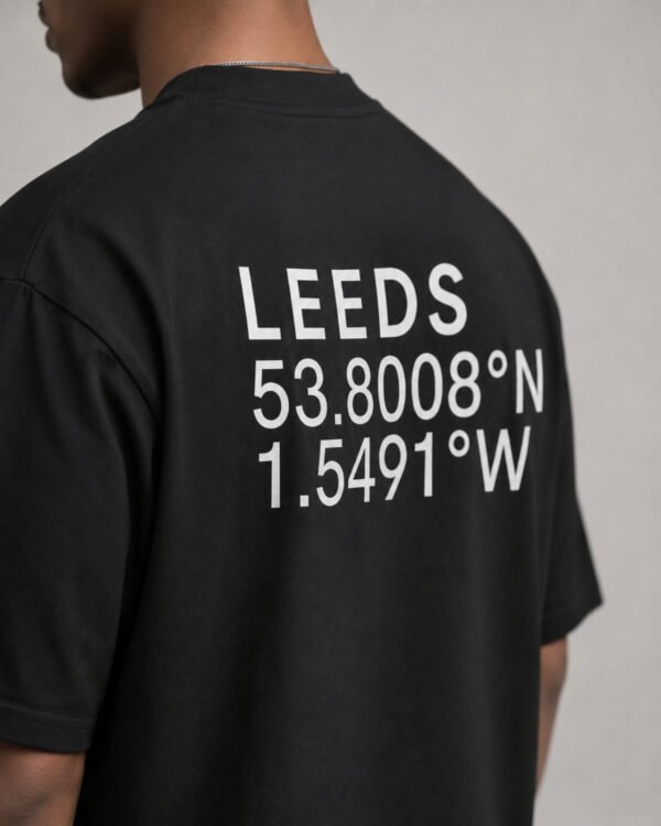 Close-up of Leeds coordinates typography printed on the back of a black oversized T-shirt, highlighting the minimalist city-inspired design.
