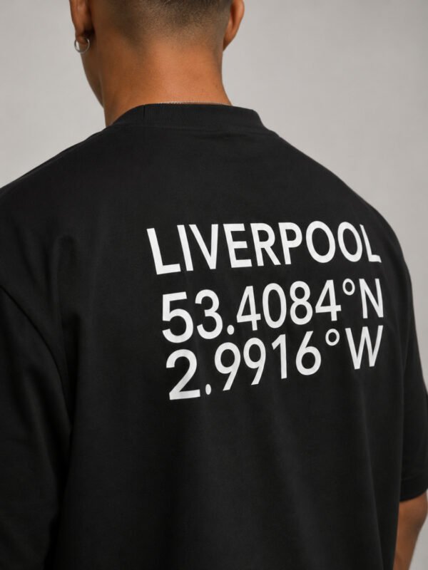 Close-up of Liverpool coordinates graphic printed on the back of a black oversized T-shirt, highlighting the clean white typography.