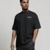 Model wearing a black oversized Liverpool T-shirt with subtle Liverpool chest logo and clean minimalist streetwear styling.