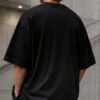Rear view of a male model wearing a black Birmingham Signature oversized heavyweight T-shirt with dropped shoulders and clean minimalist design.