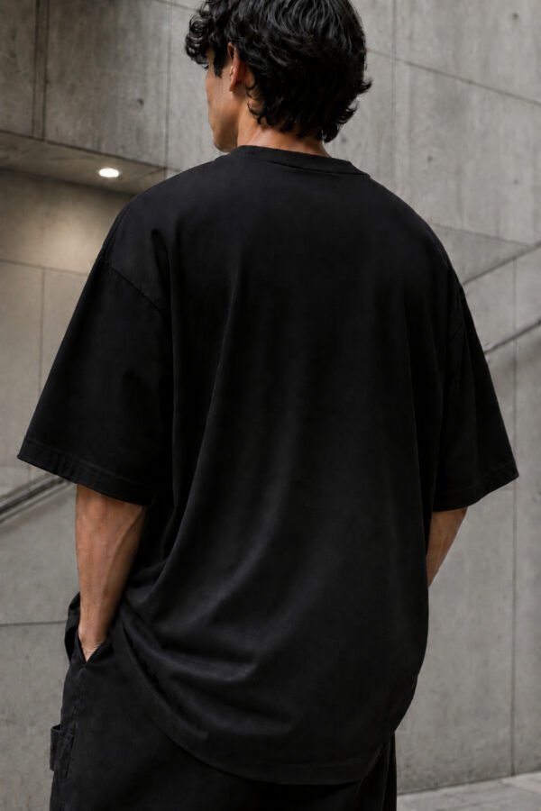 Rear view of a male model wearing a black Birmingham Signature oversized heavyweight T-shirt with dropped shoulders and clean minimalist design.