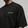 Close-up of the Manchester Signature chest print on a black oversized heavyweight T-shirt showing premium cotton fabric and clean white design.
