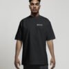 Front view of a male model wearing a black Manchester Signature oversized heavyweight T-shirt featuring a minimalist white left chest coordinates print.