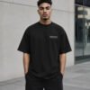 Model wearing a black Manchester Signature oversized heavyweight T-shirt with a subtle white left-chest Signature design.