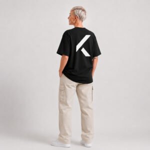 Full-length rear view of a female model wearing a black oversized Kat Krush T-shirt with a large white signature K back print and off-white cargo trousers in a minimalist studio.
