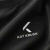 Close-up of the black Kat Krush heavyweight cotton T-shirt showing the minimalist white chest logo, premium fabric texture and soft natural folds.