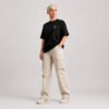 Full-length front view of a female model wearing a black oversized Kat Krush heavyweight T-shirt with a minimalist white chest logo and relaxed off-white cargo trousers.