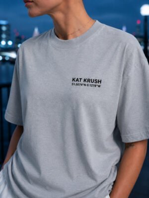 "Heather Grey oversized Kat Krush London coordinates t-shirt with black chest logo in an urban evening setting. Premium heavyweight cotton and relaxed oversized fit."