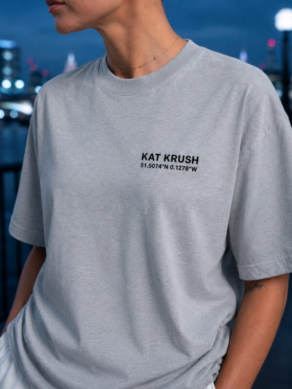 "Heather Grey oversized Kat Krush London coordinates t-shirt with black chest logo in an urban evening setting. Premium heavyweight cotton and relaxed oversized fit."