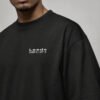 Close-up of the black Leeds Signature oversized T-shirt showing the white Leeds coordinates chest design and heavyweight fabric.