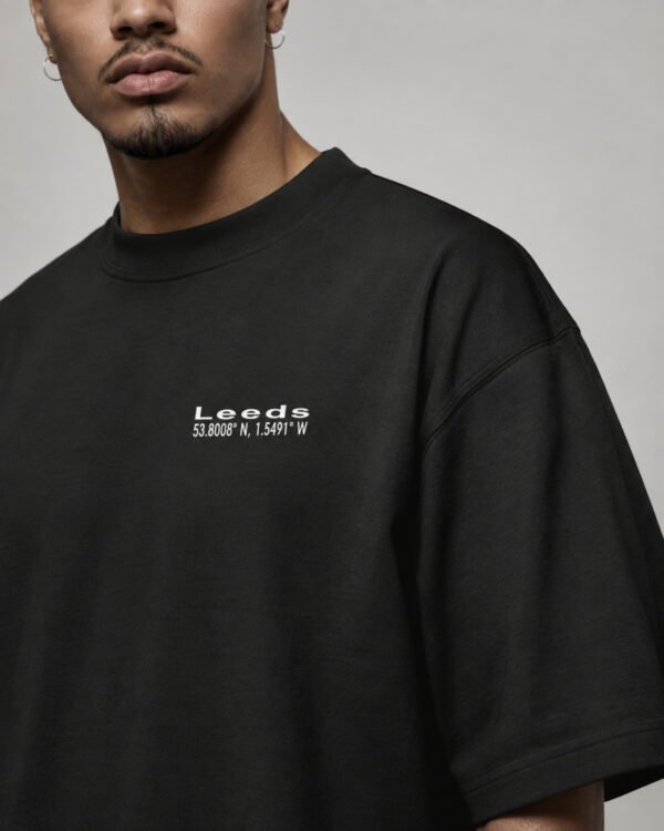 Close-up of the black Leeds Signature oversized T-shirt showing the white Leeds coordinates chest design and heavyweight fabric.