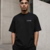 Male model wearing a black Leeds Signature oversized T-shirt against contemporary Leeds architecture.