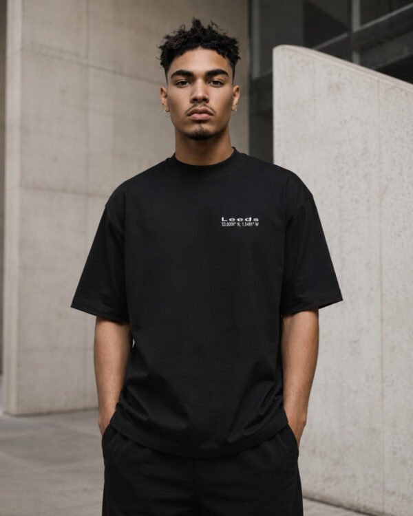 Male model wearing a black Leeds Signature oversized T-shirt against contemporary Leeds architecture.