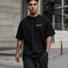 Male model walking through contemporary Leeds architecture wearing a black Leeds Signature oversized T-shirt.