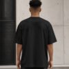 Rear view of a male model wearing a black Liverpool Signature oversized heavyweight T-shirt with dropped shoulders and a clean minimalist silhouette.