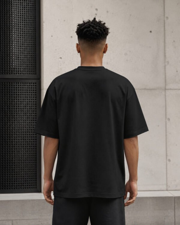 Rear view of a male model wearing a black Liverpool Signature oversized heavyweight T-shirt with dropped shoulders and a clean minimalist silhouette.