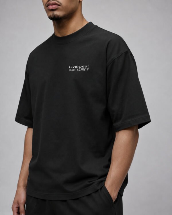 Male model wearing a black Liverpool Signature oversized heavyweight T-shirt featuring a minimalist white left chest coordinates print.