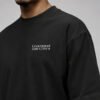 Close-up of the Liverpool Signature chest print on a black oversized heavyweight T-shirt showing the white city coordinates design and heavyweight fabric.