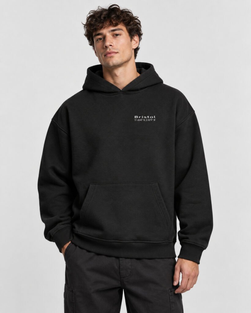 Male model wearing a black Bristol Signature heavyweight oversized hoodie with a small white left-chest design.