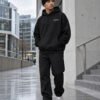 Male model wearing black Kat Krush fisherman beanie and London Signature heavyweight hoodie among pale concrete and glass architecture