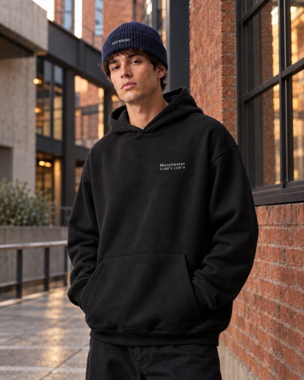Male model wearing French Navy Kat Krush fisherman beanie and black Manchester Signature heavyweight hoodie in red brick Manchester architecture