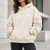 kk Confident Cream Hoodie Portrait Female model wearing Kat Krush Not Loud Just Powerful oversized hoodie in natural raw with charcoal jeans against pale contemporary architecture.