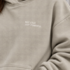 kk Stone Hoodie with Powerful Simplicity Close-up of Kat Krush stone oversized hoodie showing heavyweight cotton-blend texture, kangaroo pocket stitching and white Not Loud Just Powerful artwork.